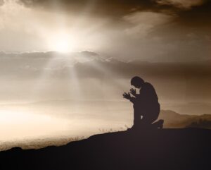 man praying worshipping abding on mountain top clouds silhouette Courtesy of CHOATphotographerShutterstockcom_246310249